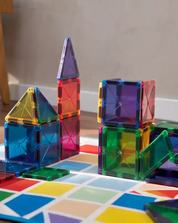 Colorful translucent Magna-Tiles magnetic building tiles stacked into towers on a patterned play mat
